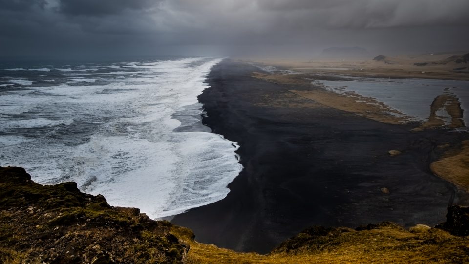 Weiße Wellen an schwarzem Strand